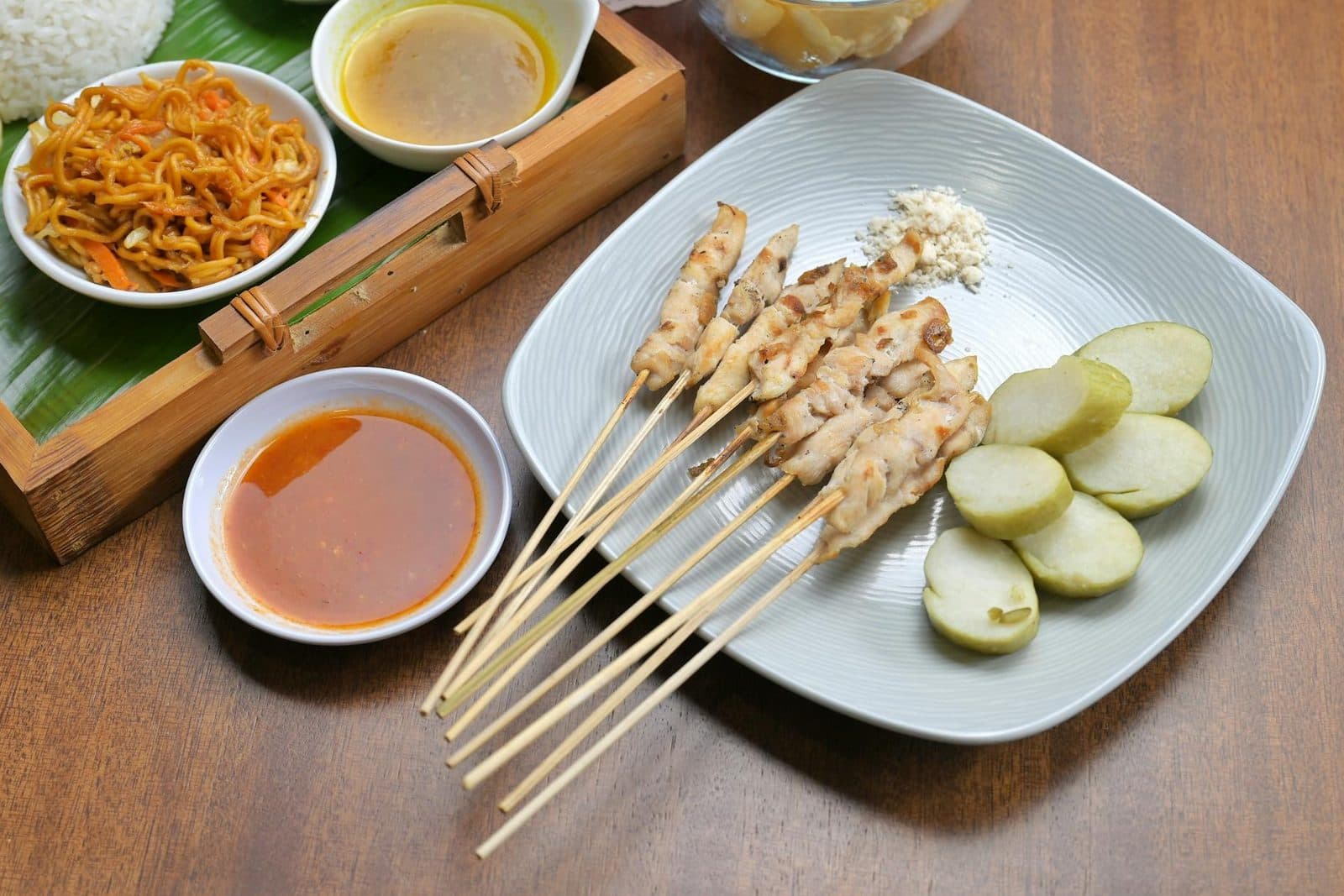 Chicken satay skewers served with peanut sauce, lime, and a small noodle side