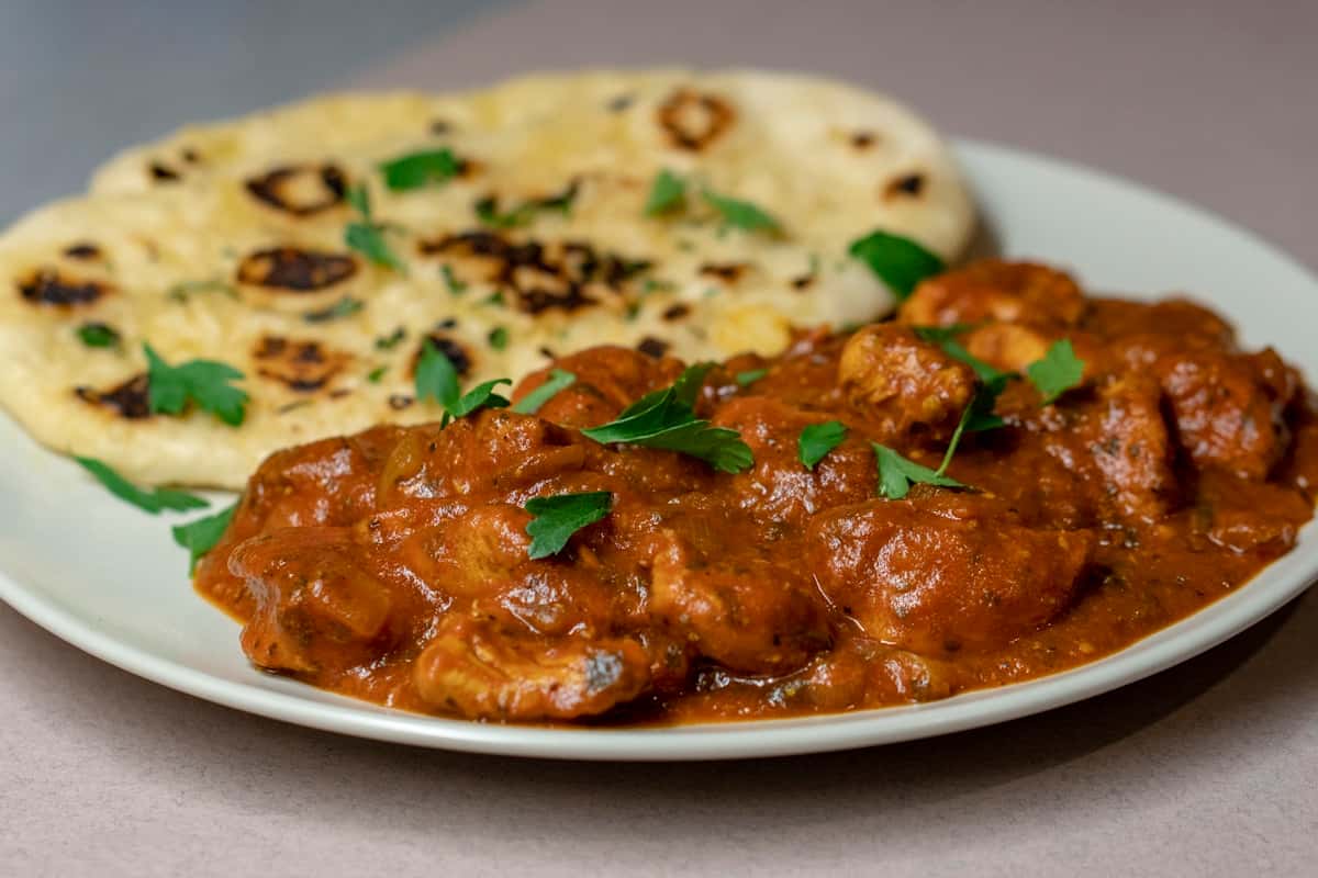 Chicken tikka masala in a rich orange-red sauce served with naan