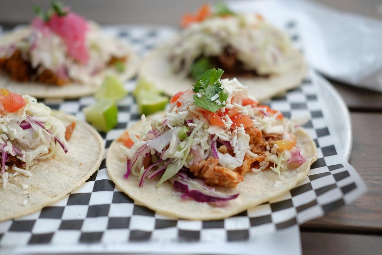 Chicken tinga tacos with shredded chicken, cabbage, lime, and fresh toppings