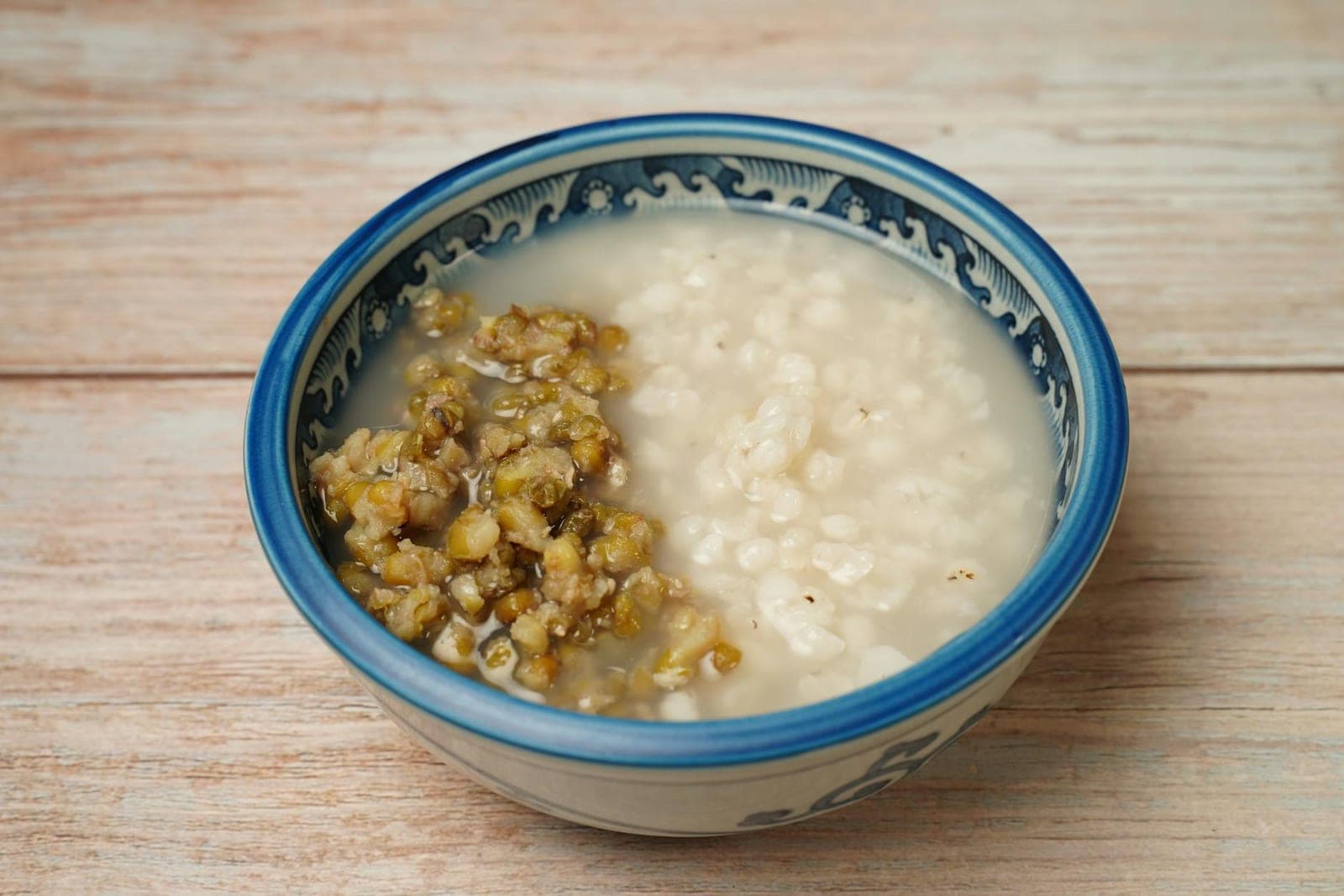 Chinese congee rice porridge in a blue and white bowl with mung beans on top