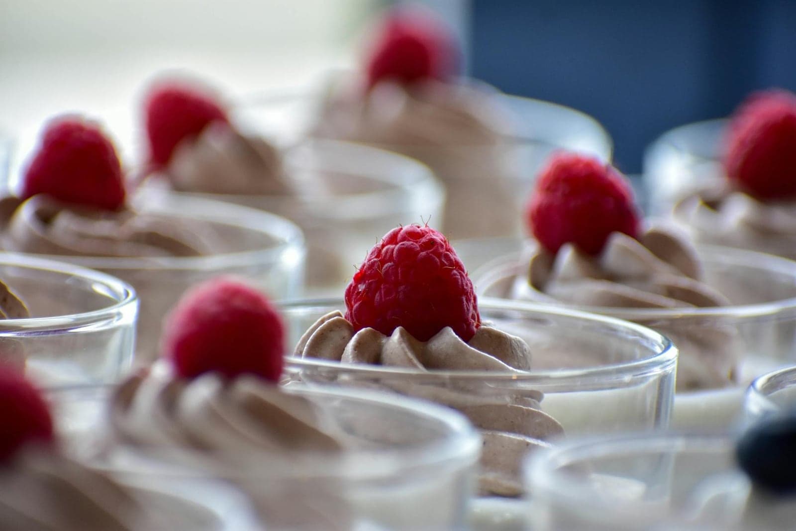 Chocolate mousse cups topped with raspberries and softly whipped cream