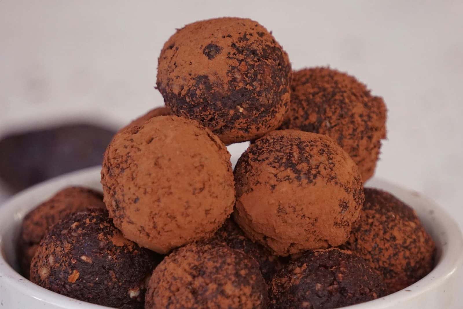 Chocolate truffles coated in cocoa powder and stacked on a white plate