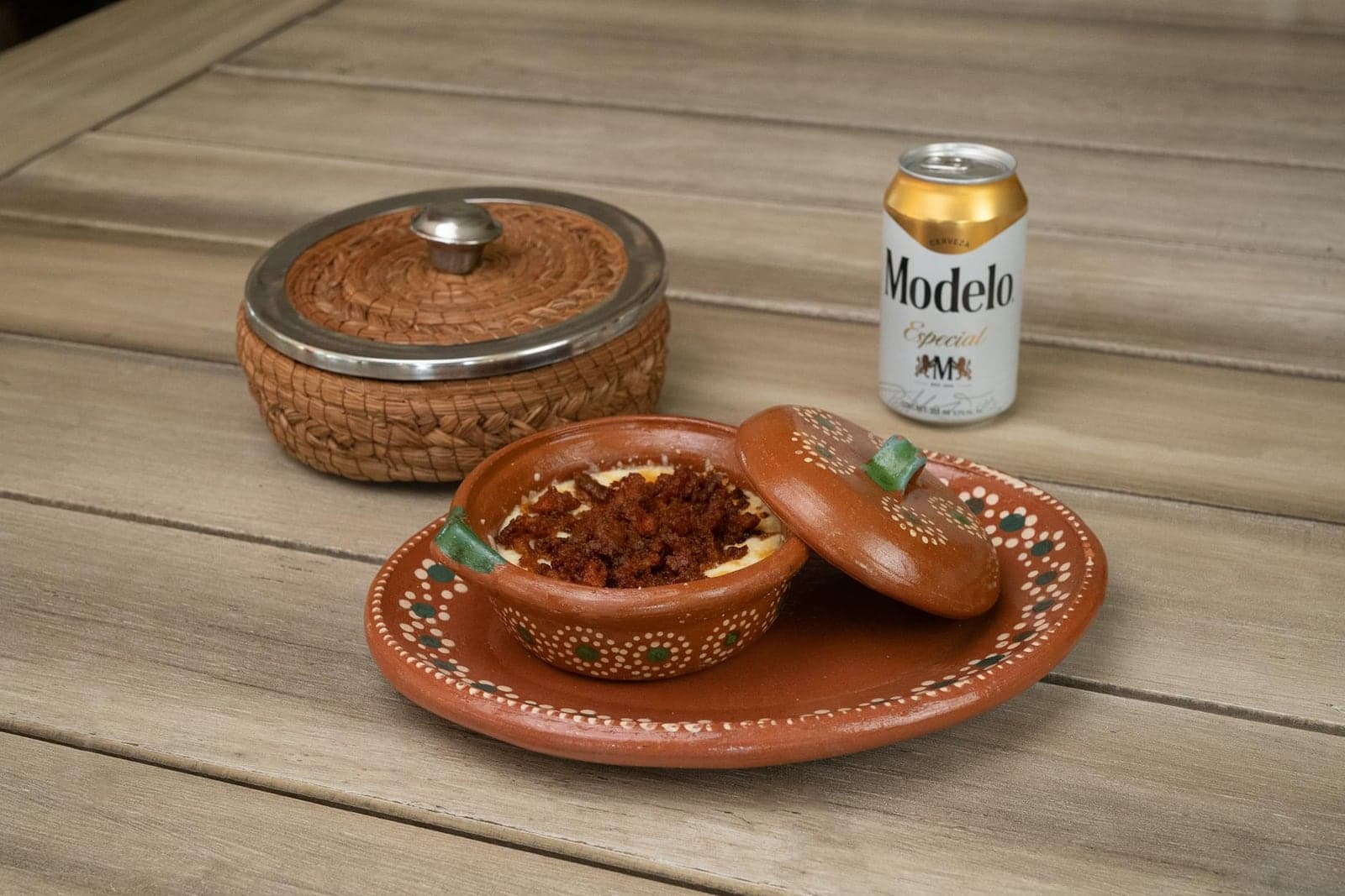 Chorizo queso dip served in a small clay dish with melted cheese and spiced topping