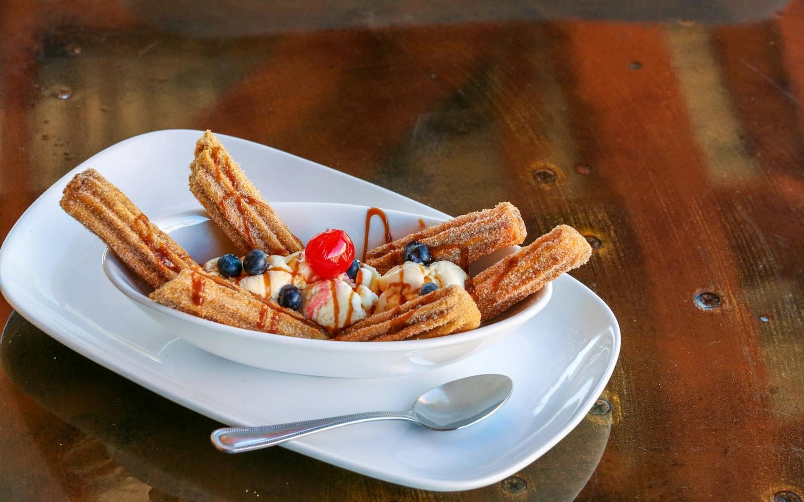 Churro ice cream dessert with churros, ice cream, blueberries, and cherry
