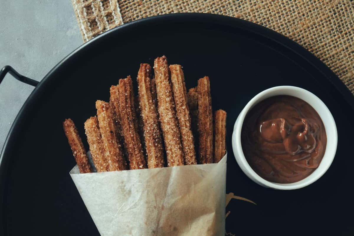 Cinnamon sugar churros with dark chocolate dipping sauce in a small bowl