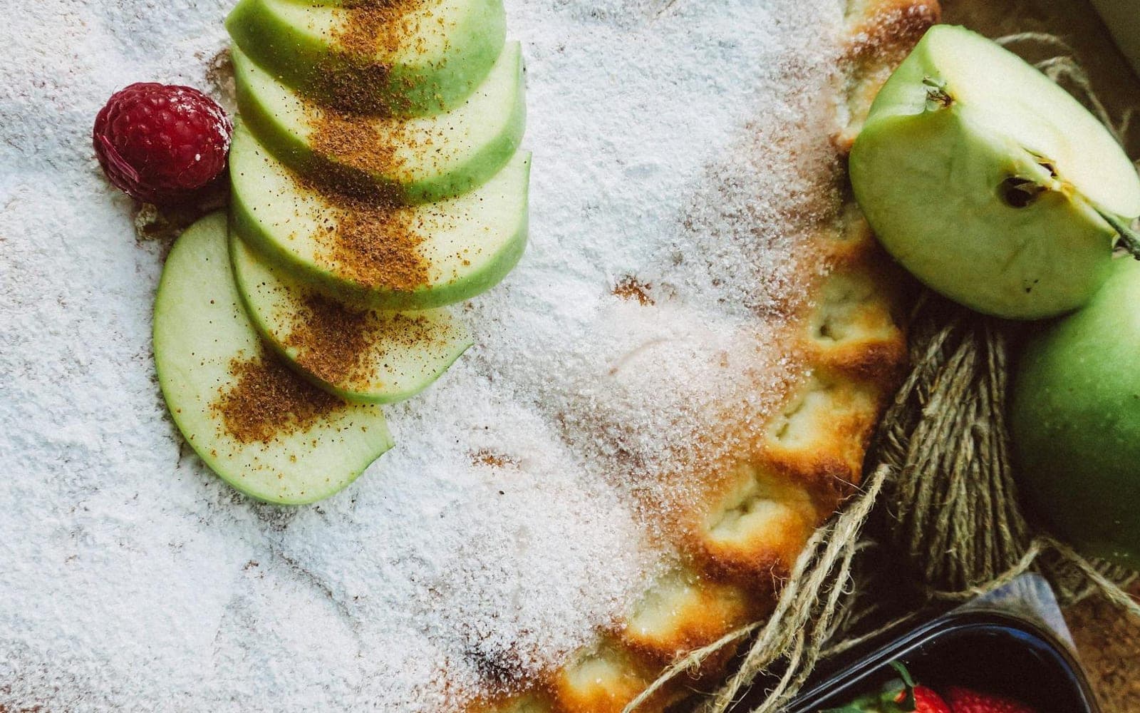 Classic apple pie with apple slices and powdered sugar on a floured surface