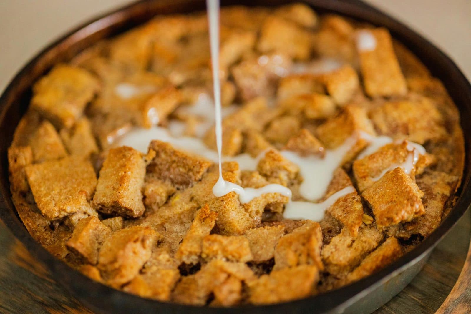 Classic bread pudding baked until golden with cream drizzled over the custardy top
