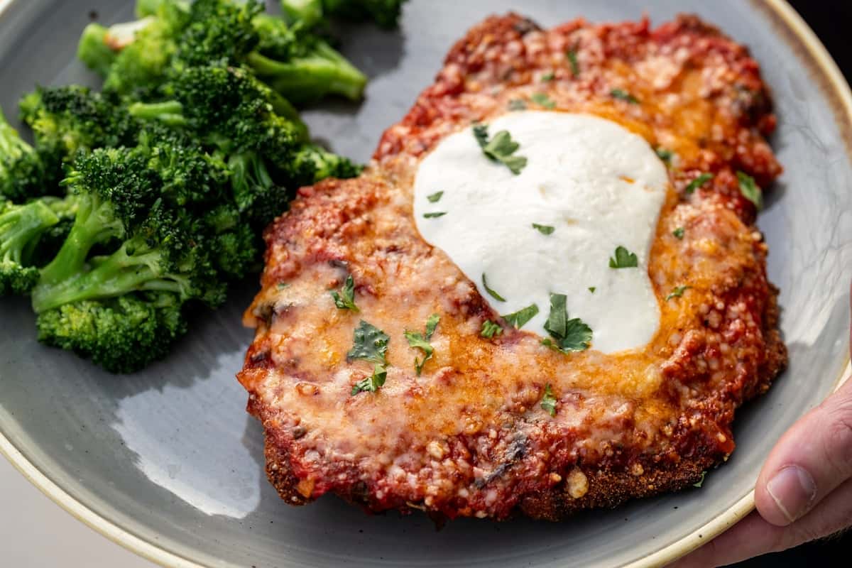 Classic chicken parmesan cutlet with melted mozzarella, marinara, and broccoli