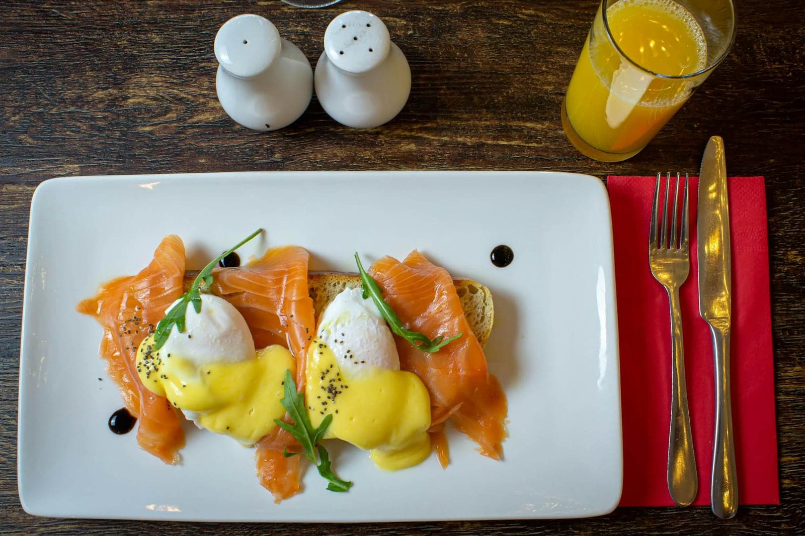 Classic eggs Benedict with poached eggs, hollandaise, salmon, and toast on a white plate