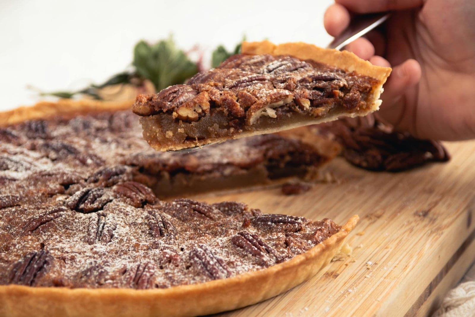 Classic pecan pie with glossy nut filling and a sliced wedge lifted from the pan