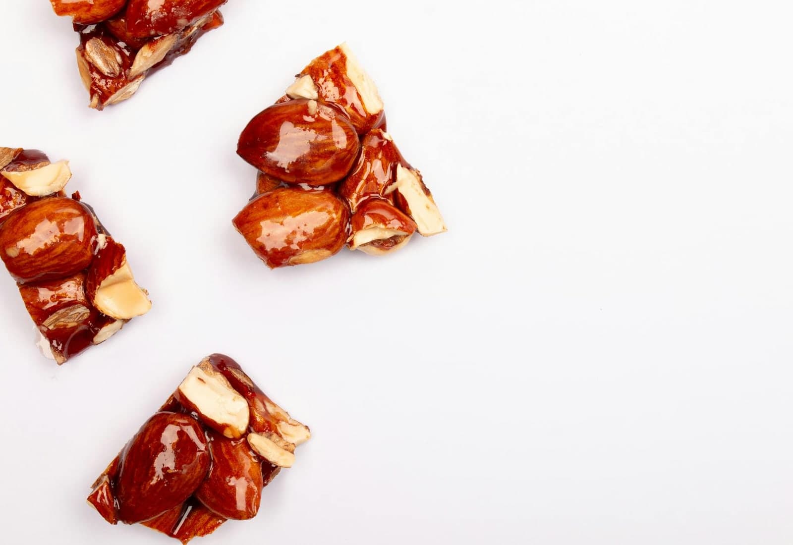 Classic peanut brittle candy pieces with glossy caramel and roasted peanuts on a white surface