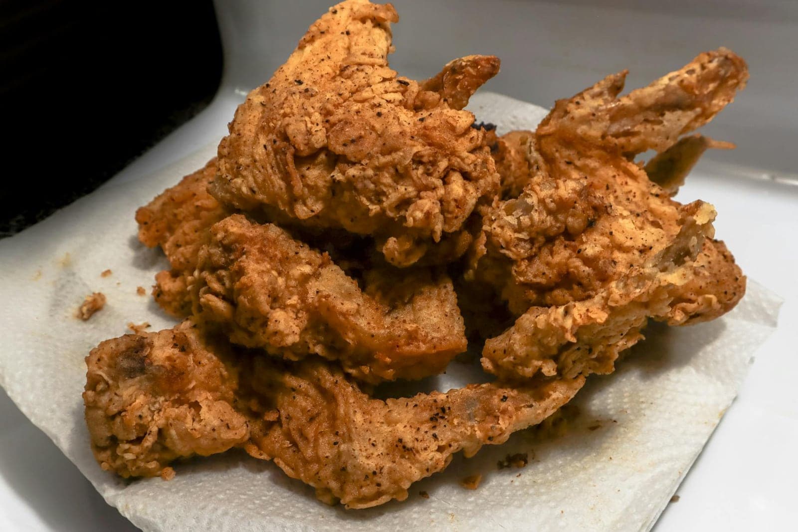 Classic Southern fried chicken with a crisp golden crust stacked on a paper-lined plate