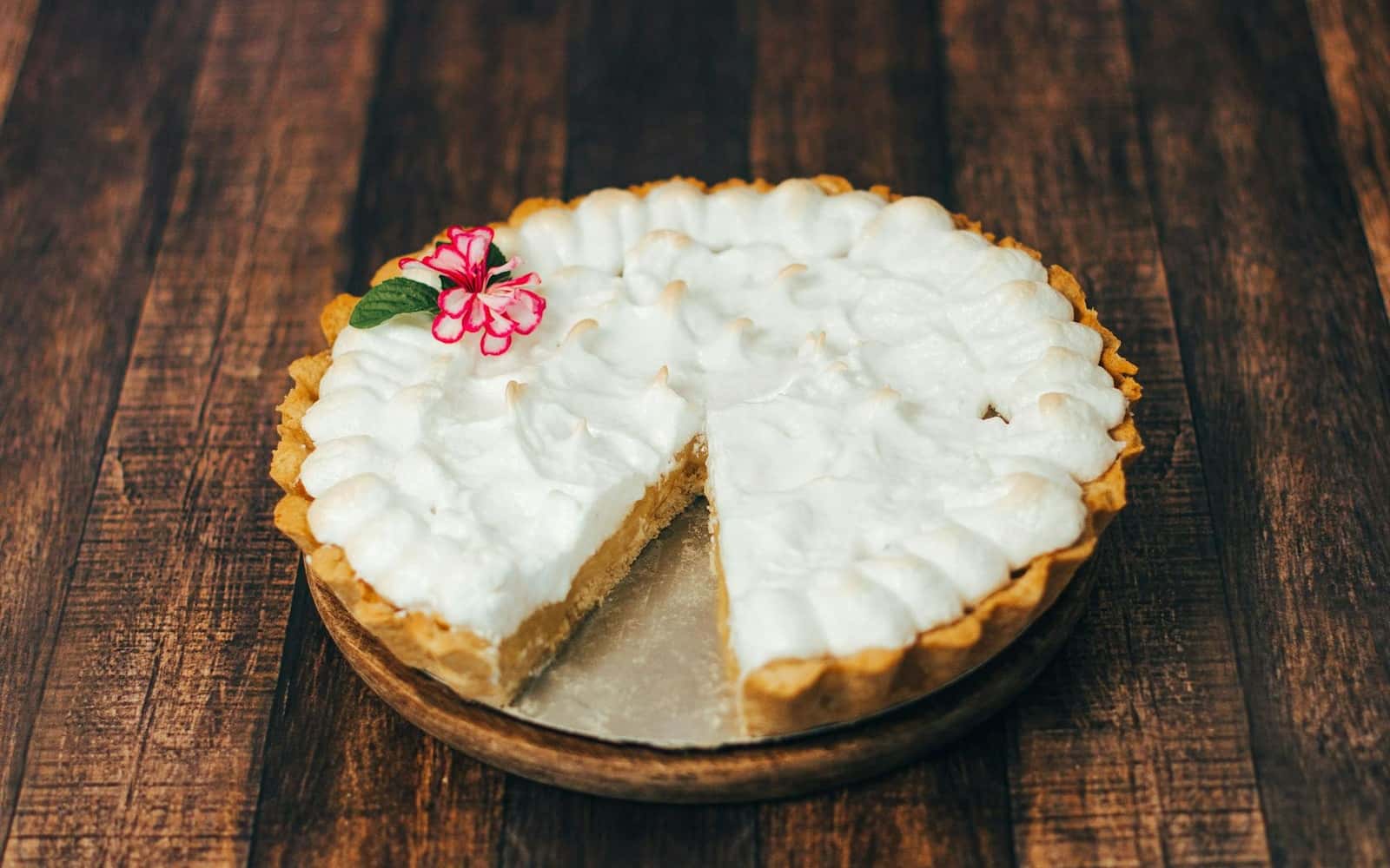 Coconut cream pie with whipped topping and a sliced creamy filling on a wooden table