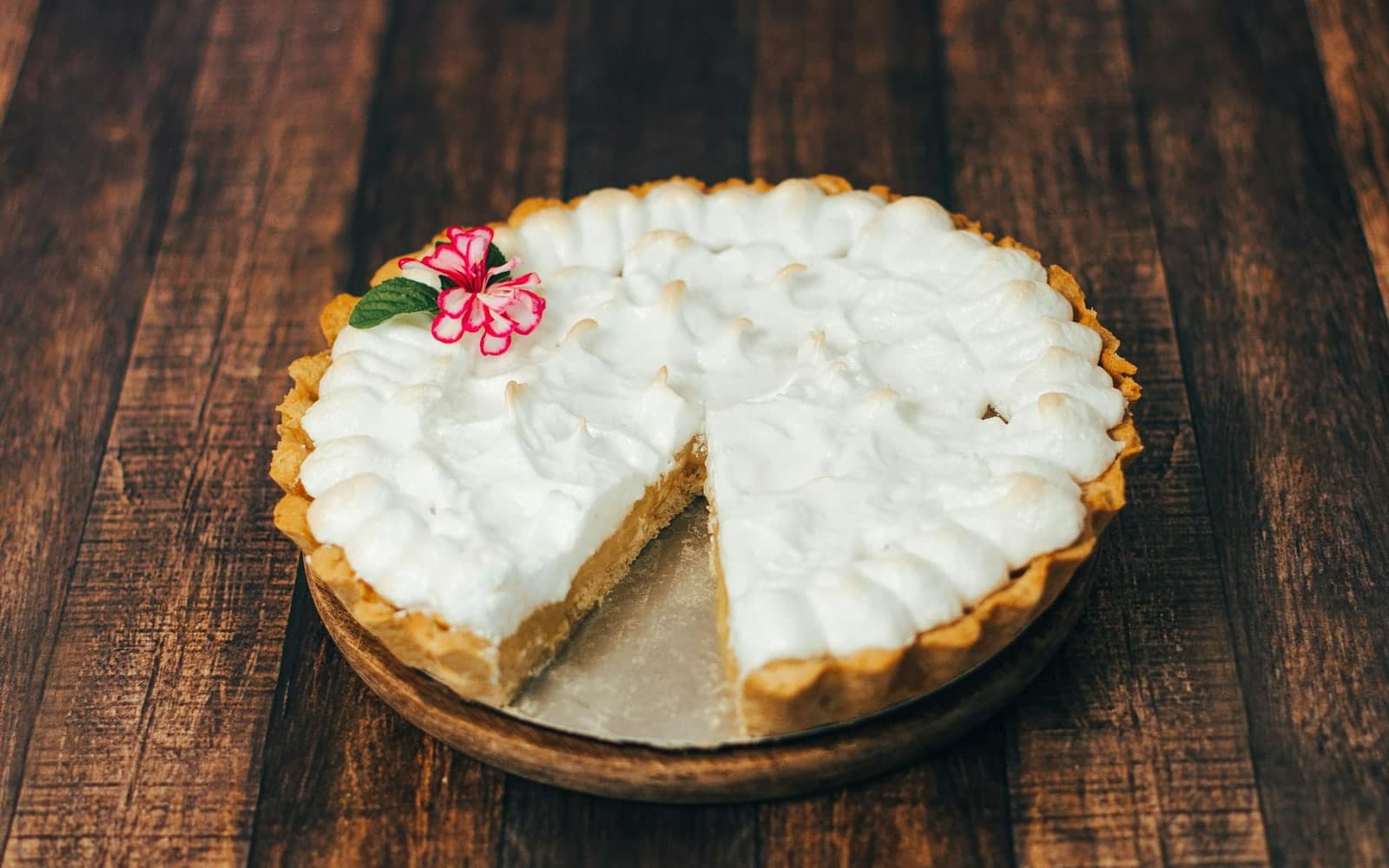 Coconut cream pie with whipped topping and a sliced creamy filling on a wooden table
