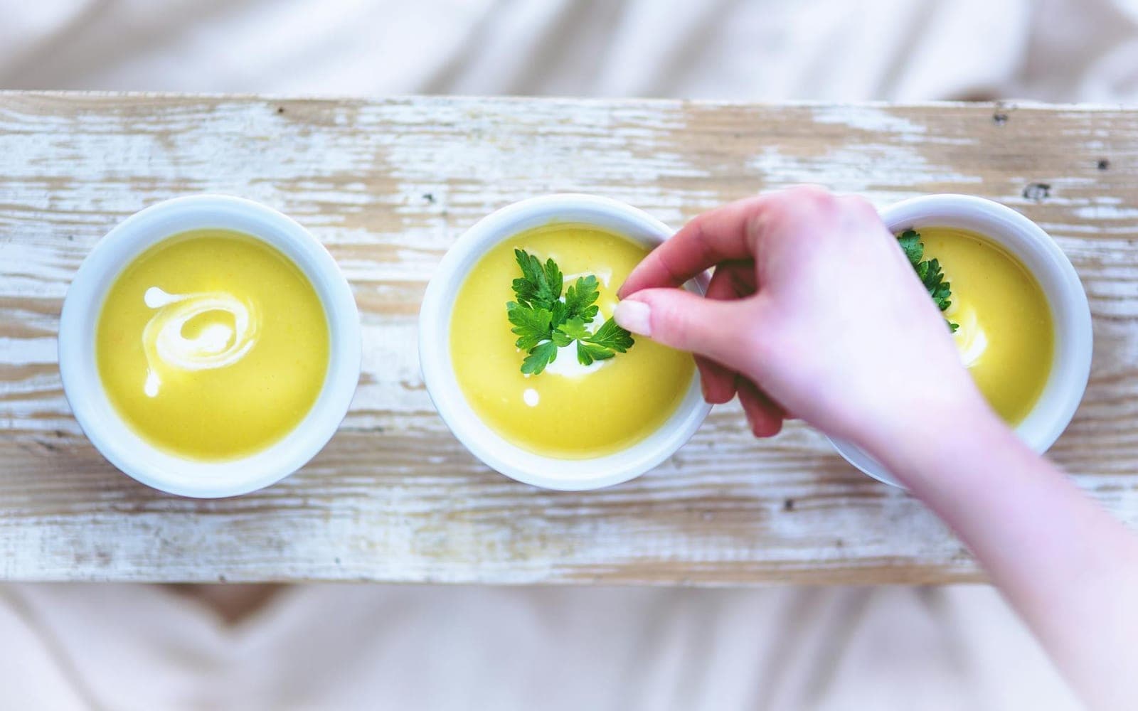Creamy baked potato soup bowls being garnished with herbs
