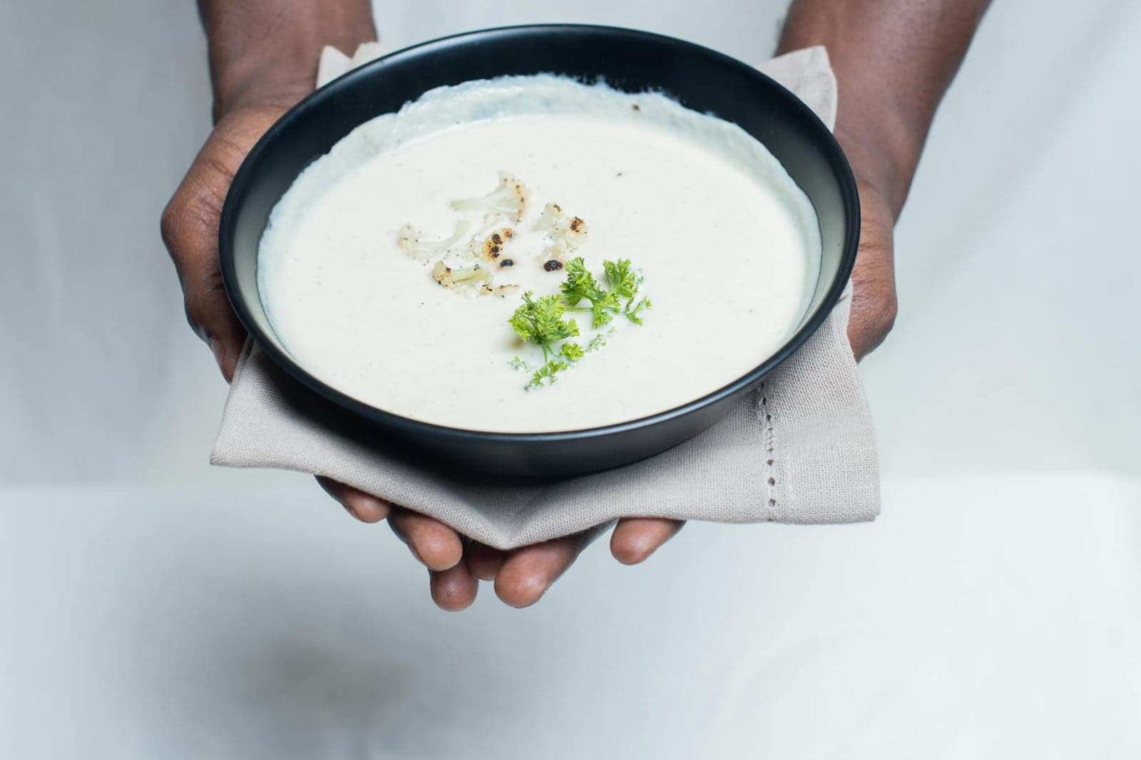 Creamy cauliflower leek soup in a black bowl with parsley garnish