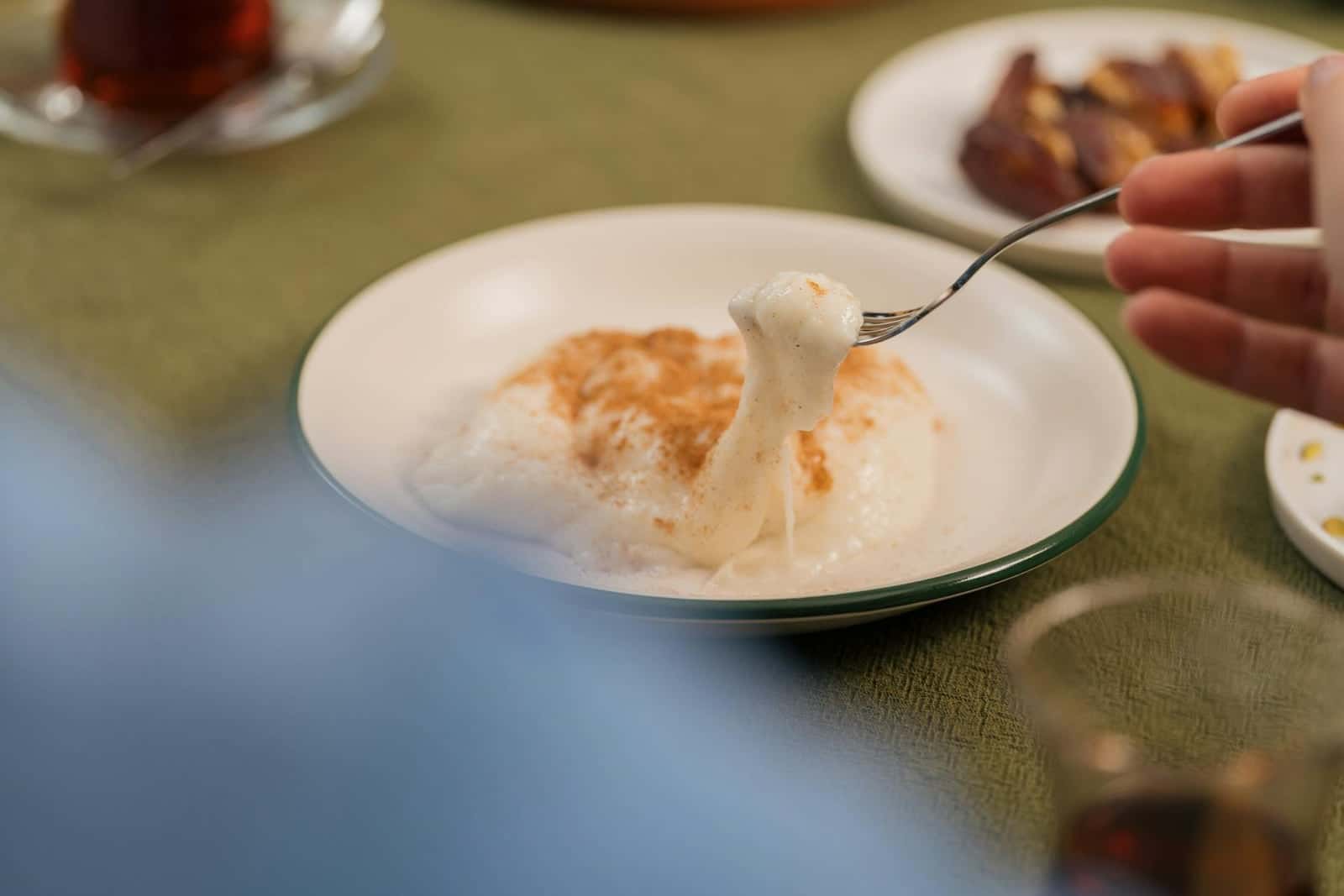 Creamy rice pudding with cinnamon being lifted from a shallow bowl with a spoon