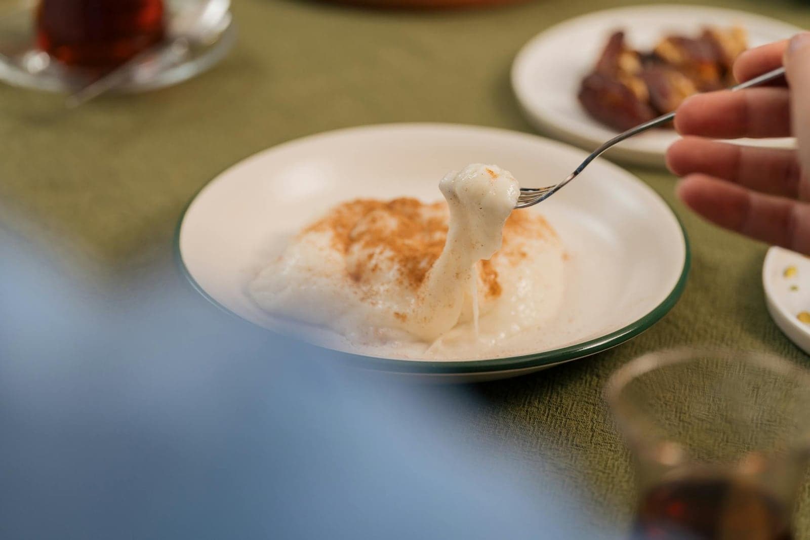 Creamy rice pudding with cinnamon being lifted from a shallow bowl with a spoon