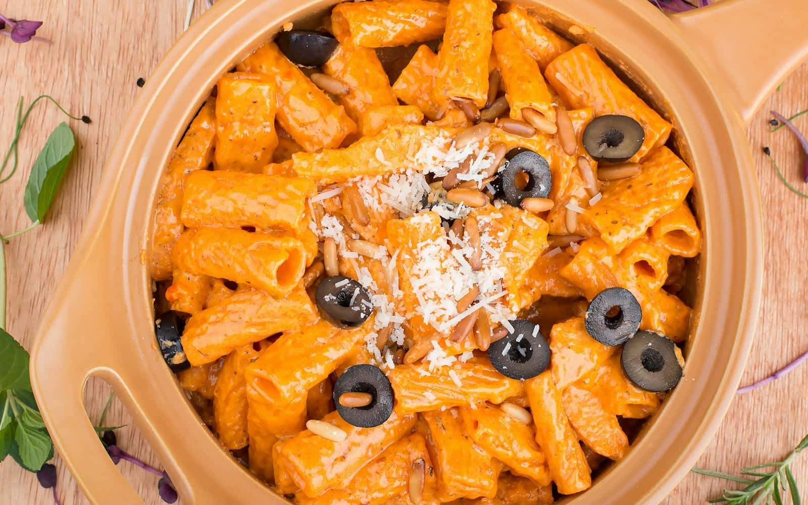 Creamy Tuscan rigatoni with orange sauce, olives, herbs, and parmesan