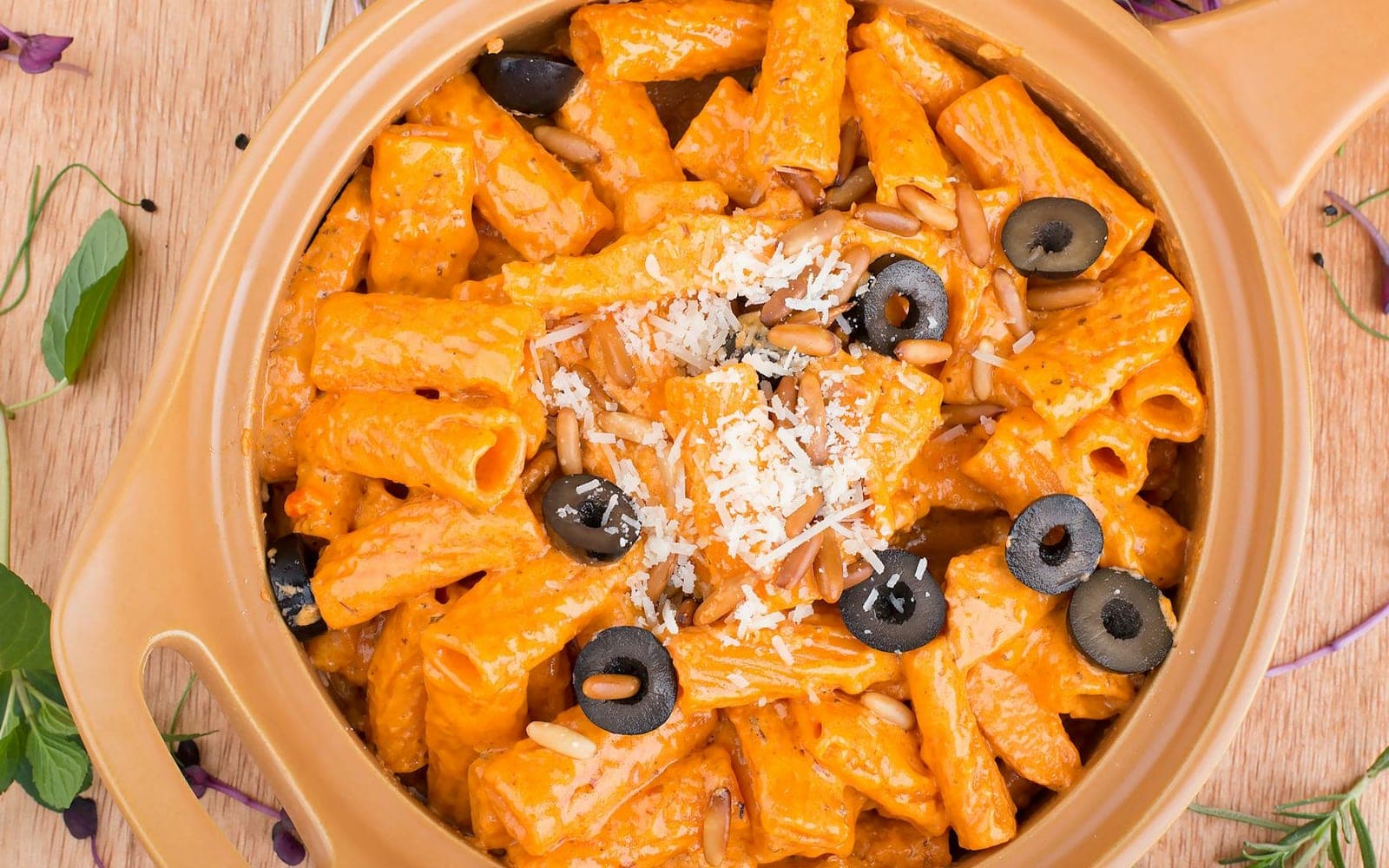 Creamy Tuscan rigatoni with orange sauce, olives, herbs, and parmesan