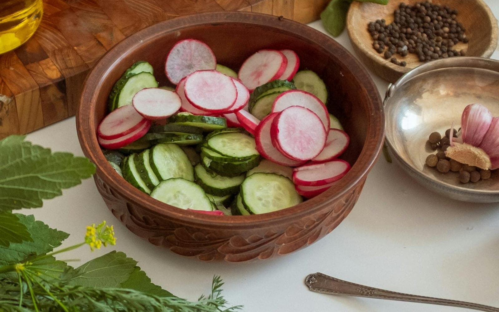 Cucumber dill salad with sliced cucumbers, radishes, and herbs in a wooden bowl