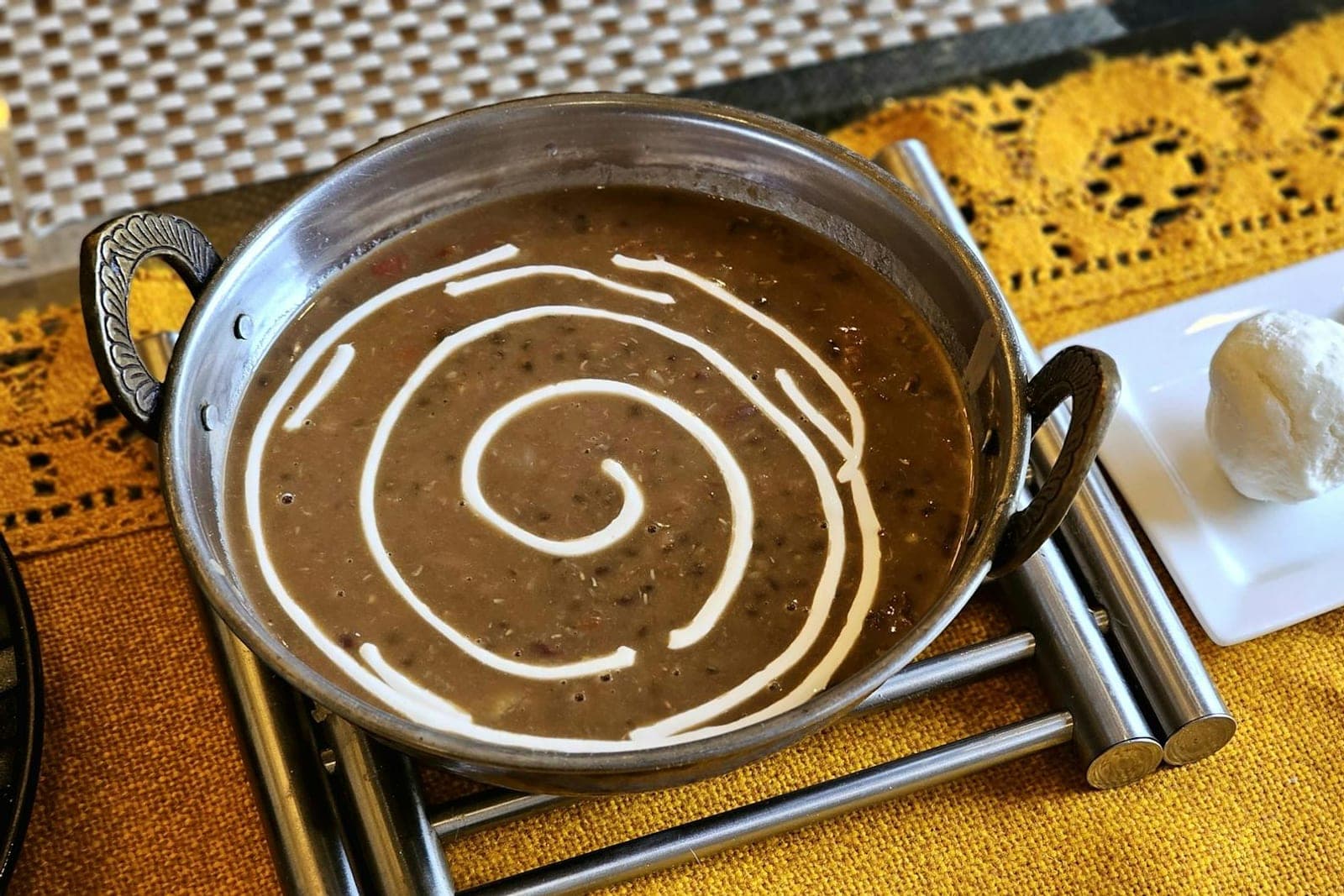 Dal makhani black lentil curry with a cream swirl in a metal serving bowl