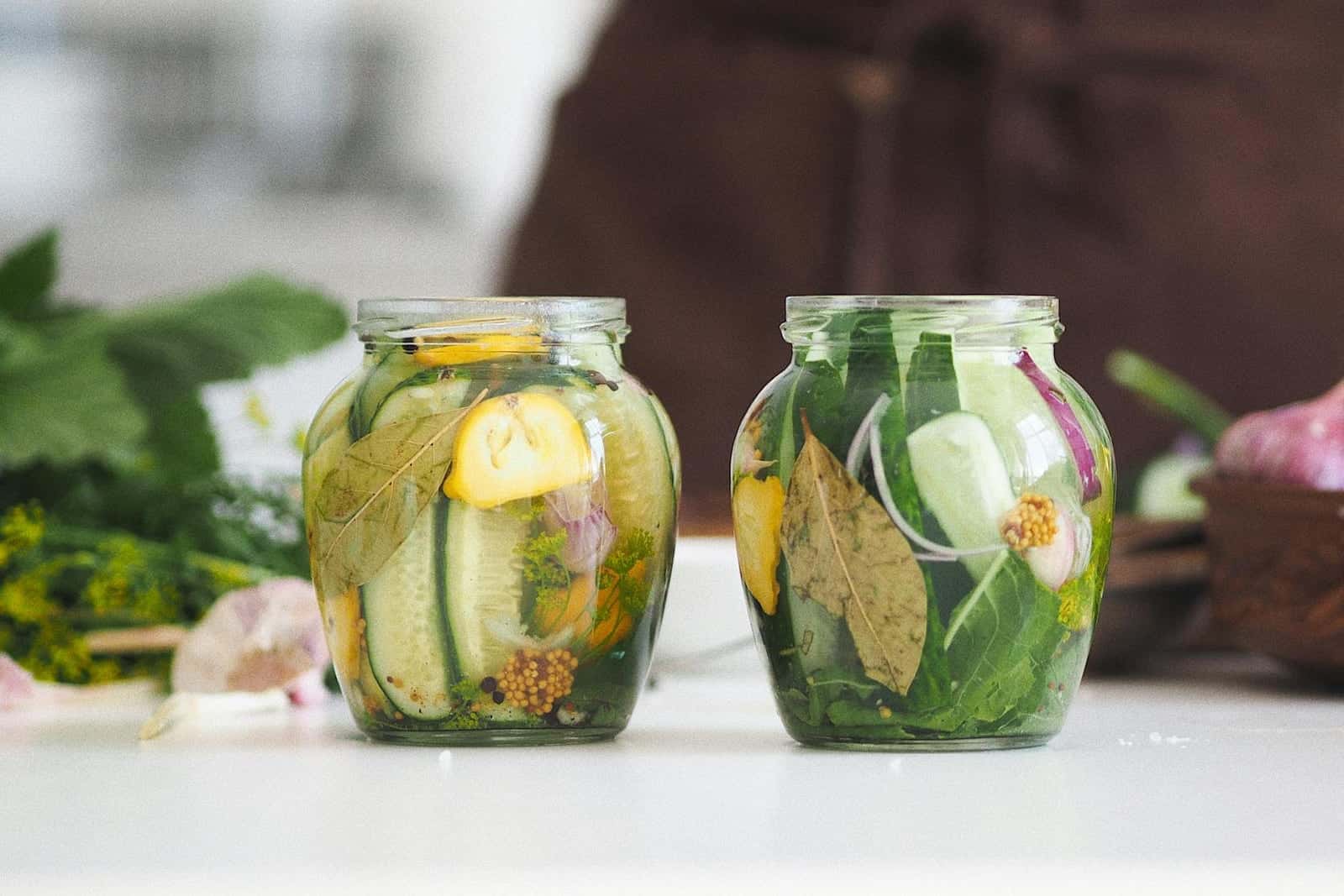 Homemade dill pickles packed in glass jars with cucumbers, herbs, and brine