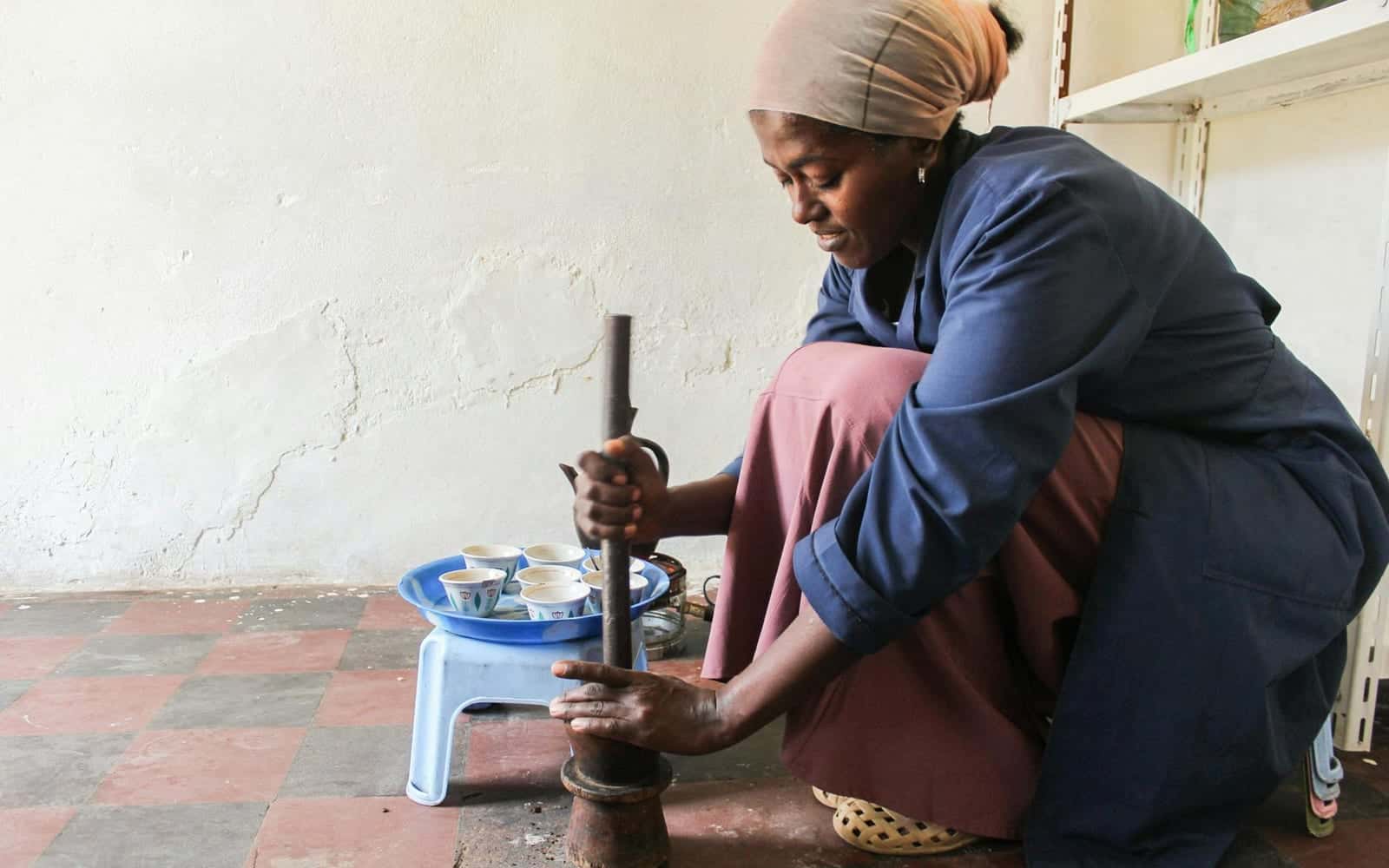 Ethiopian coffee ceremony preparation with coffee being ground by hand