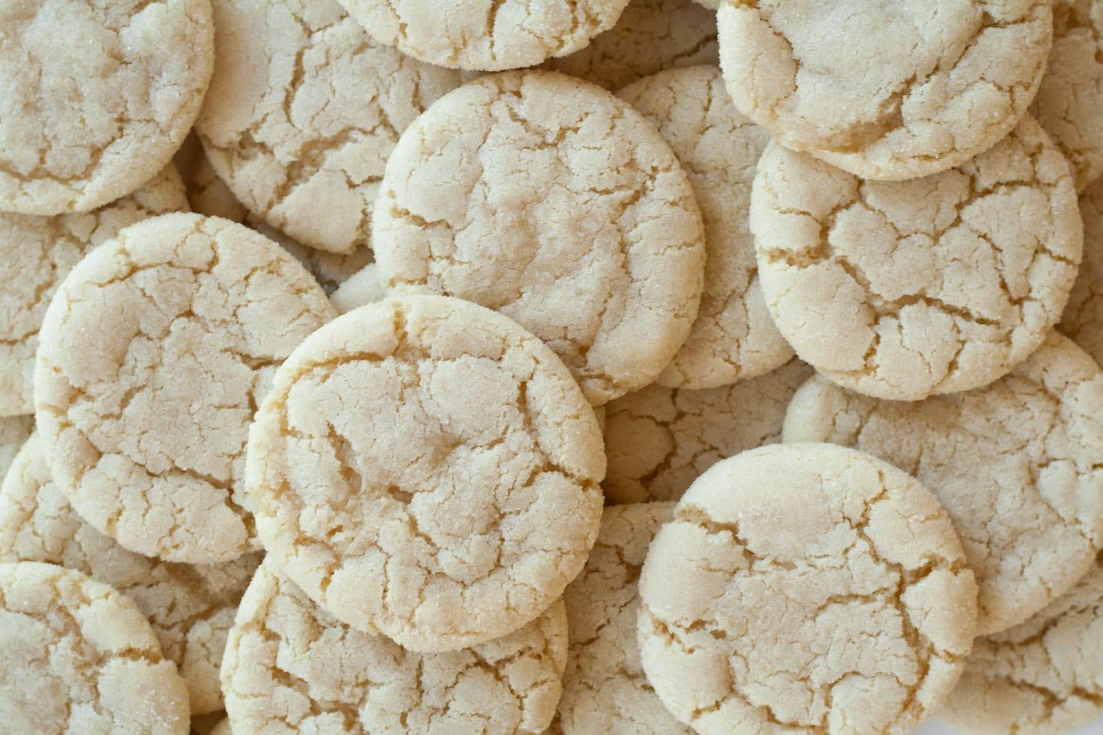 Fancy snickerdoodles with pale crackly cinnamon-sugar tops arranged in a close stack