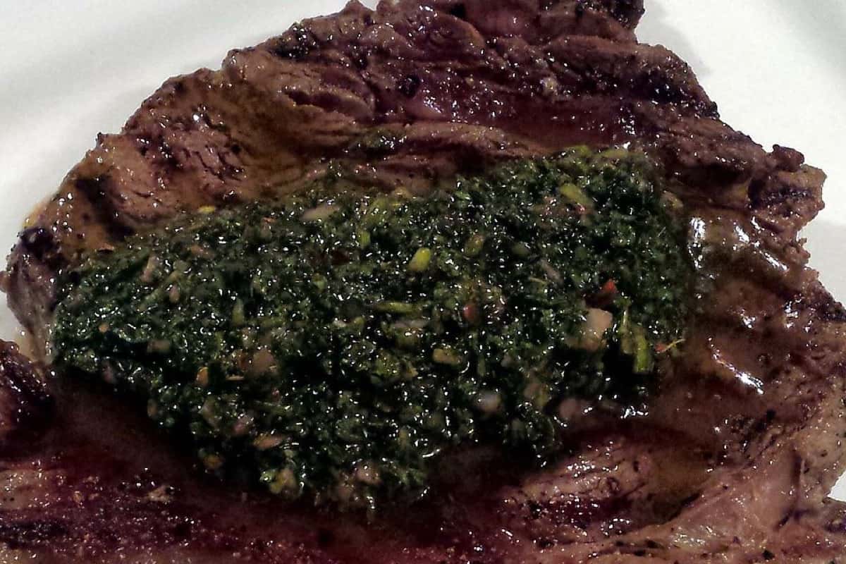 Grilled steak topped with green chimichurri sauce