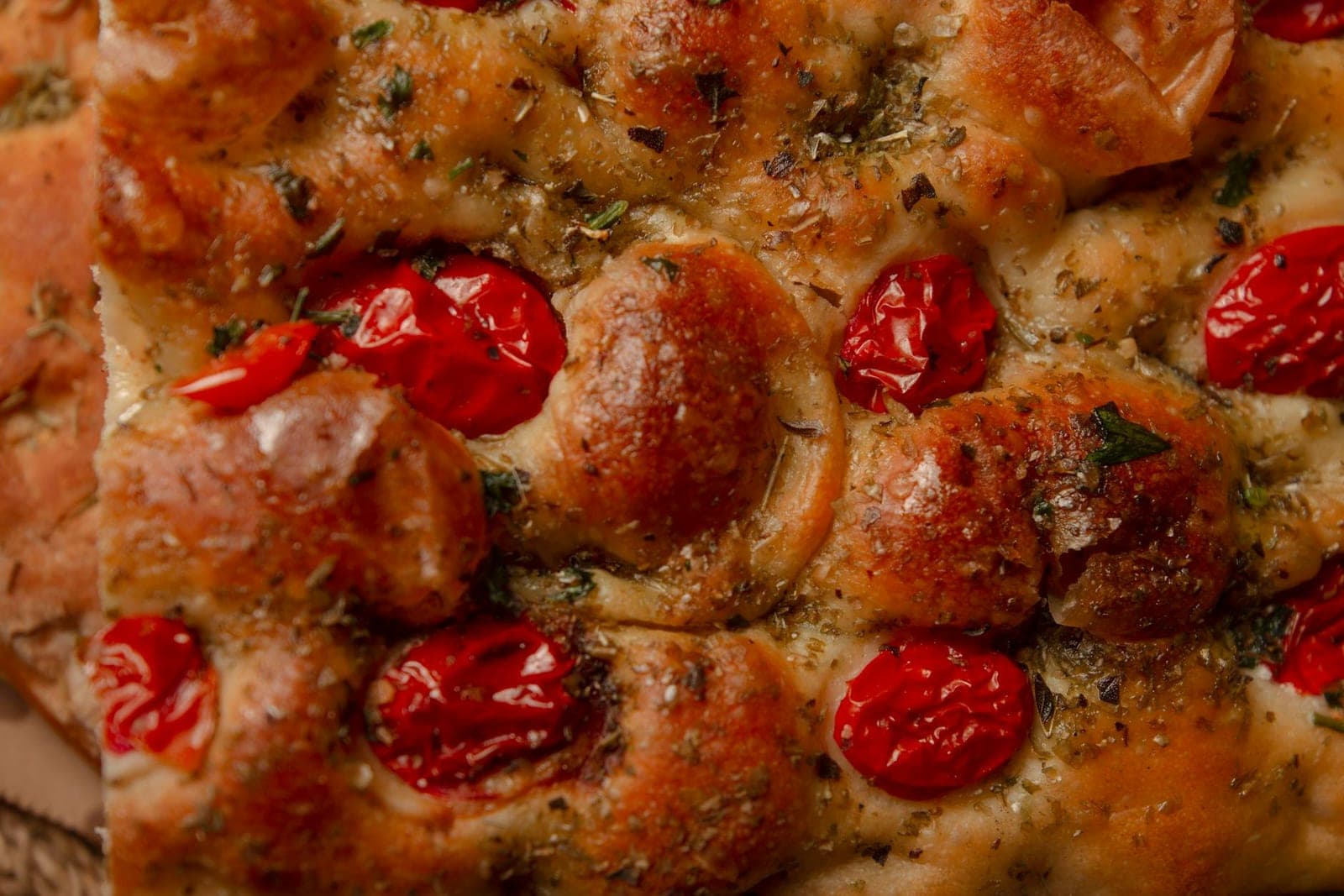 Focaccia with garden toppings, cherry tomatoes, herbs, and browned dimples