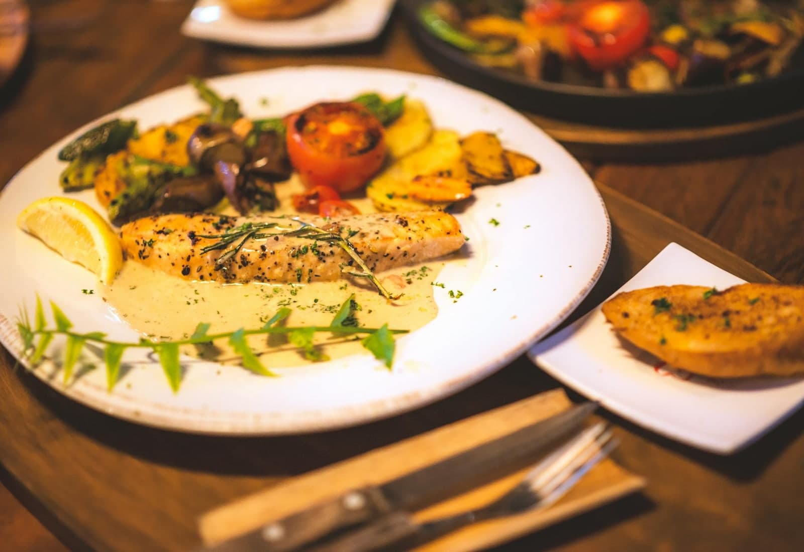 French salmon en papillote-style herbed salmon with lemon and roasted vegetables on a plated dinner table