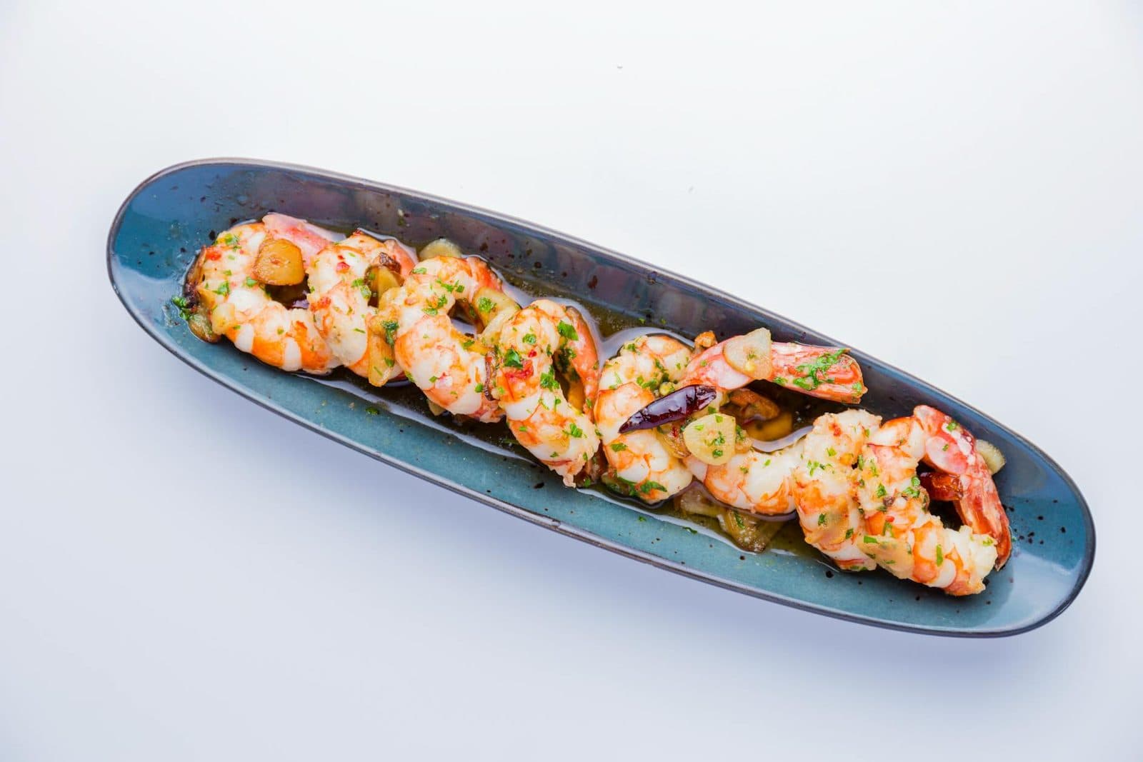 Gambas al ajillo shrimp in a blue dish with garlic, herbs, and a glossy sauce