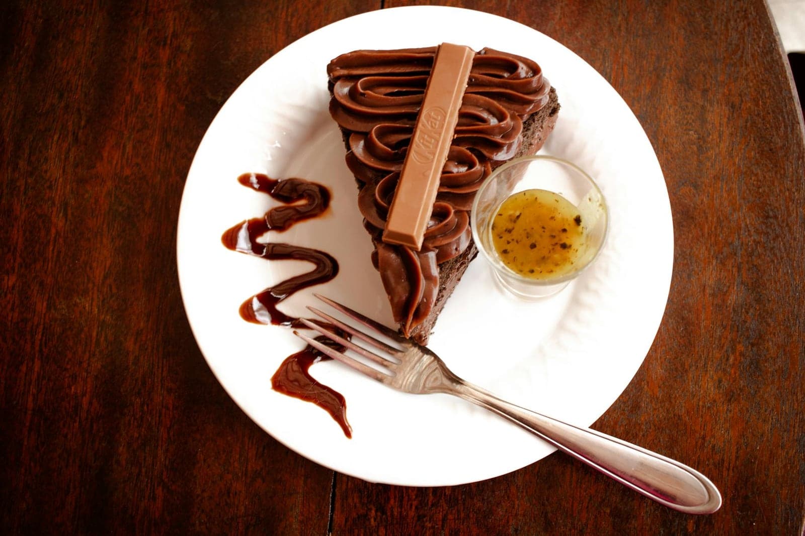 Gluten-free chocolate cake-style slice with glossy chocolate topping on a white plate