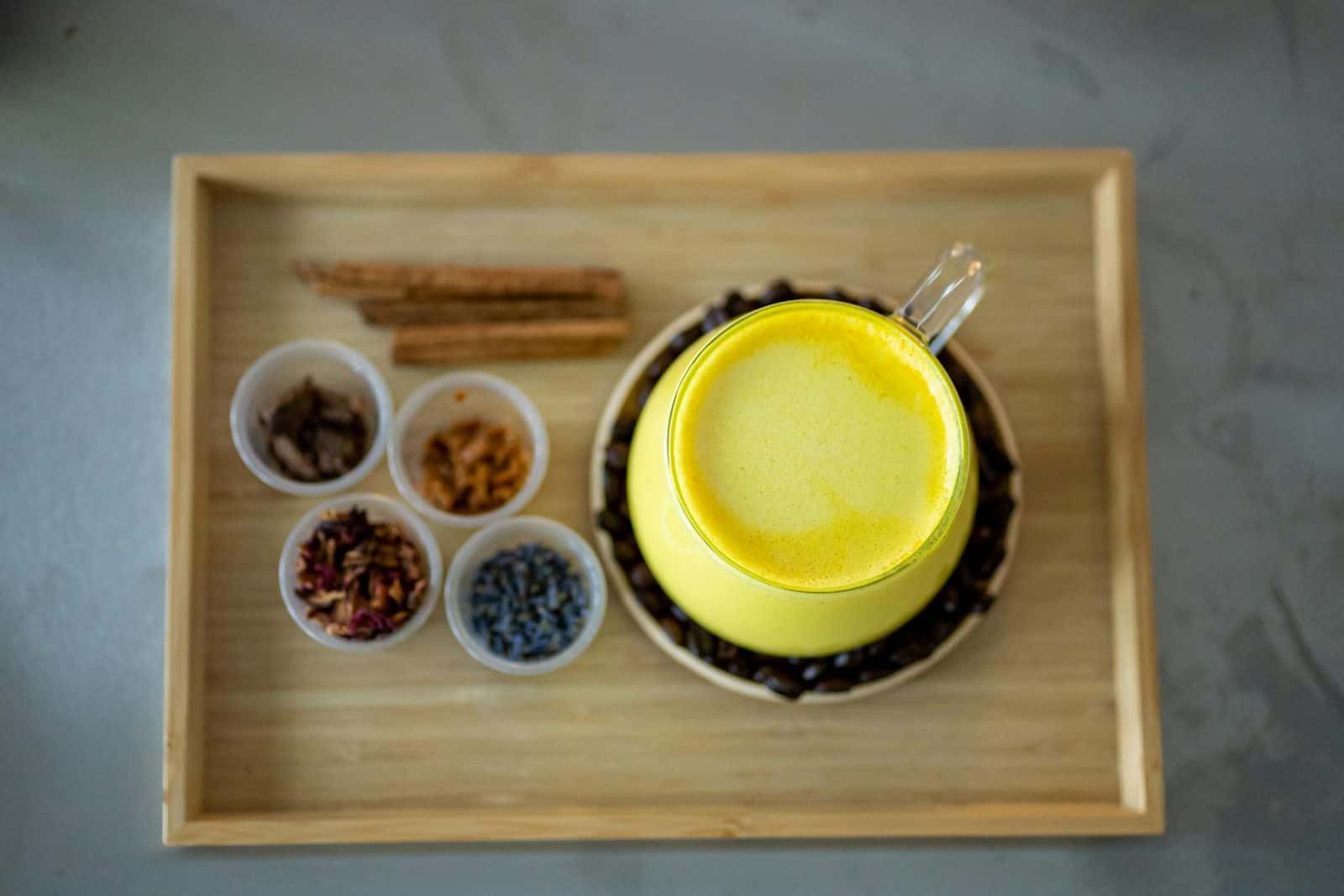 Golden milk latte with turmeric spices arranged around a bright yellow drink