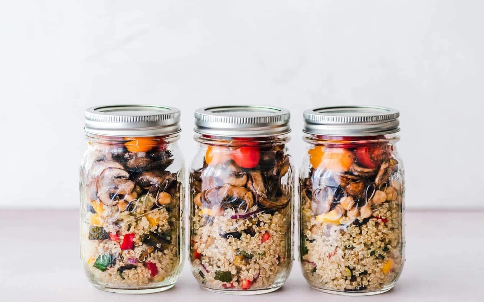 Grain salad meal prep jars with quinoa, roasted vegetables, and beans