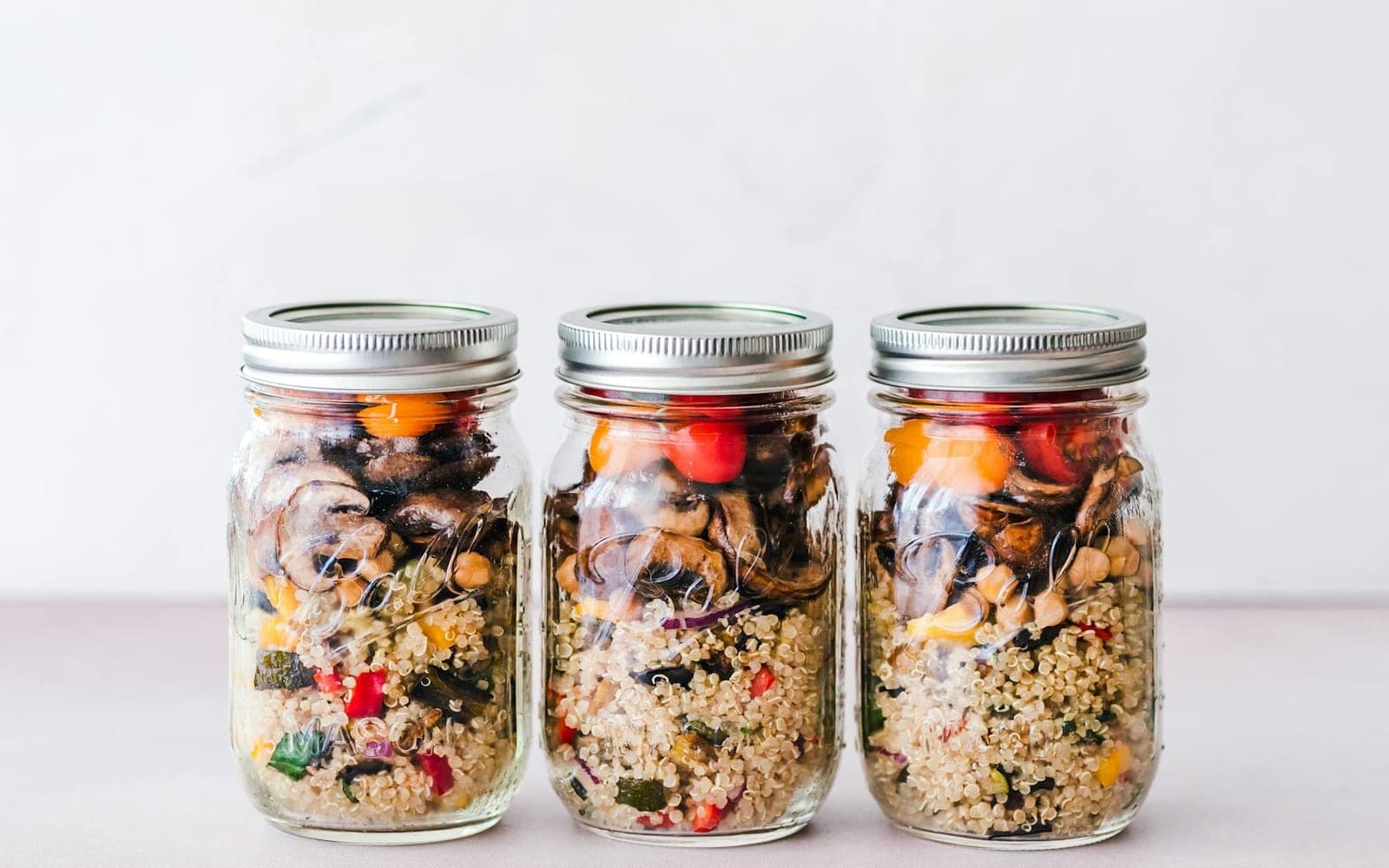 Grain salad meal prep jars with quinoa, roasted vegetables, and beans