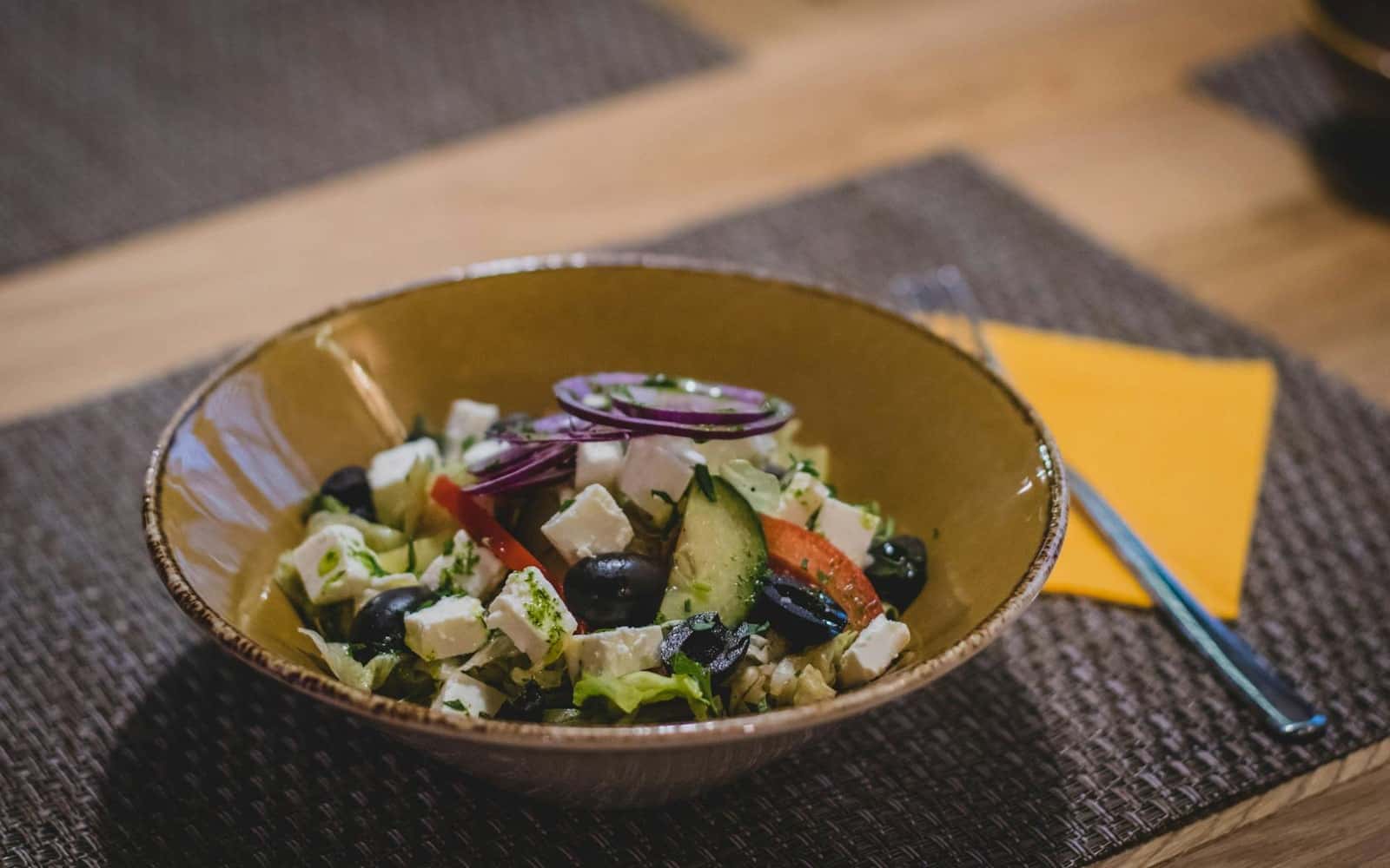 Greek orzo salad with feta, olives, cucumber, and vegetables in a rustic bowl