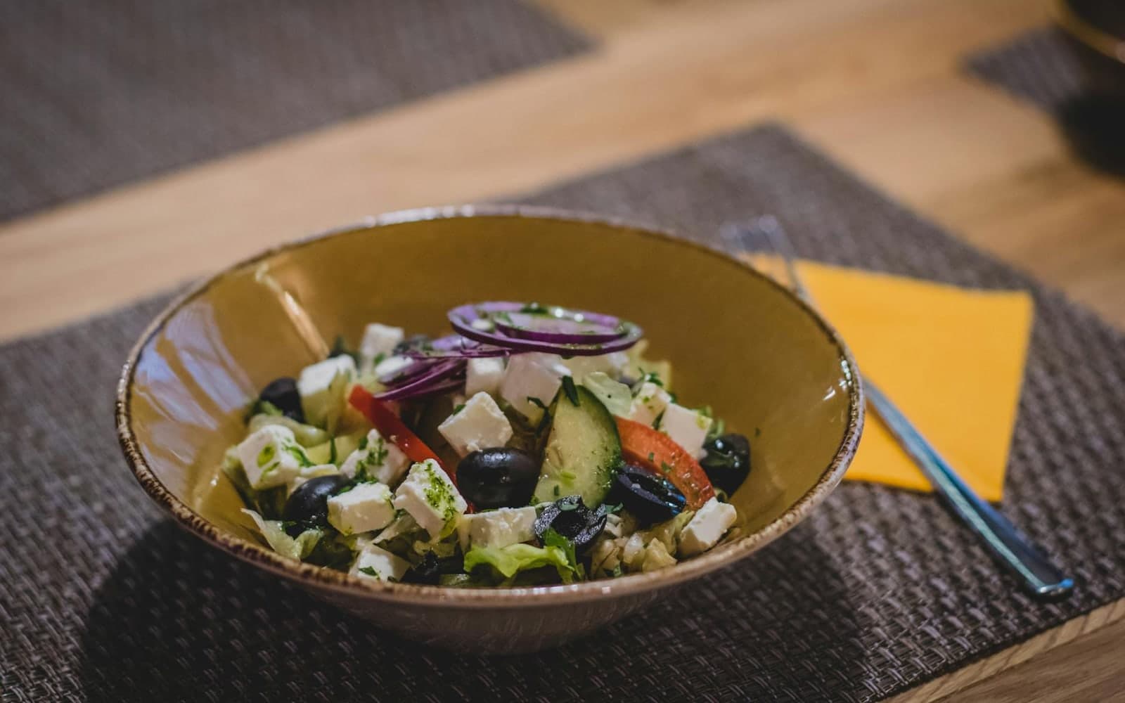 Greek orzo salad with feta, olives, cucumber, and vegetables in a rustic bowl