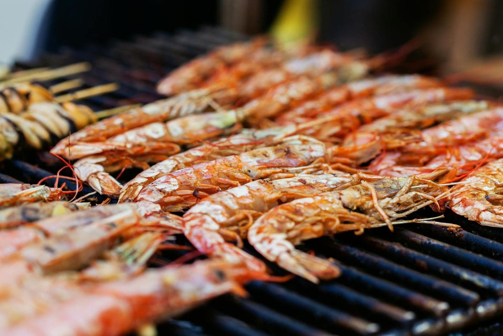 Honey lime shrimp skewers grilling over open flame with charred shells and bright citrus flavor