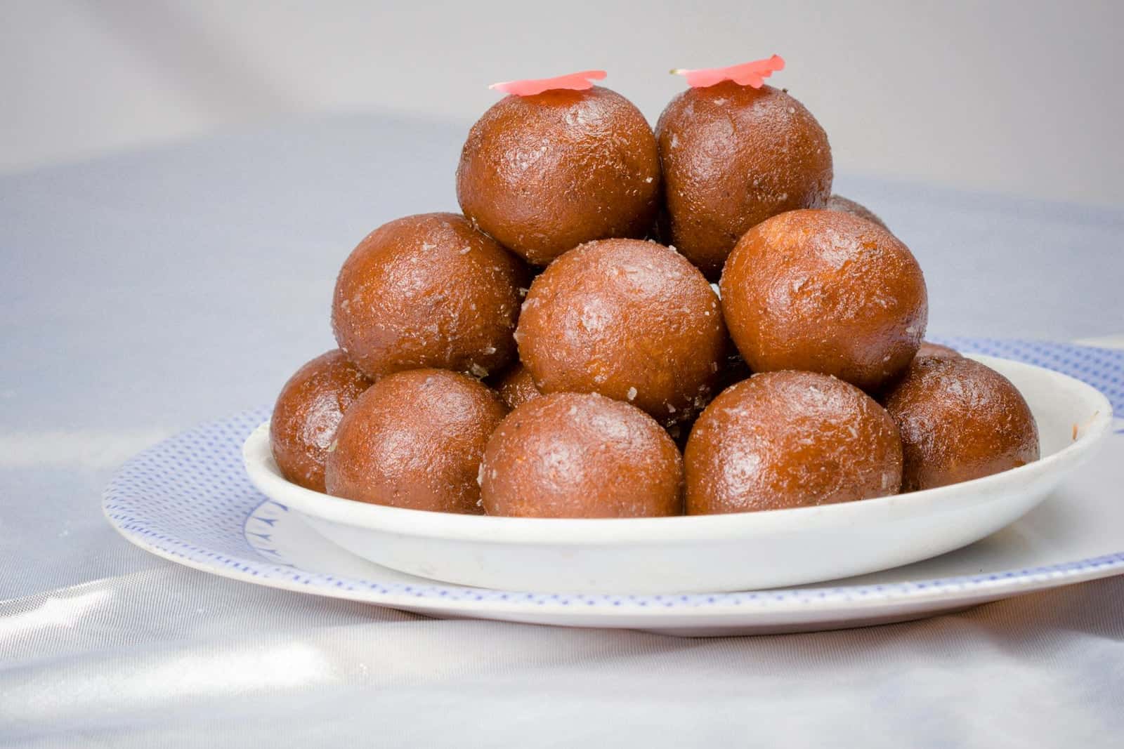 Gulab jamun arranged in a pyramid on a white plate with glossy syrup