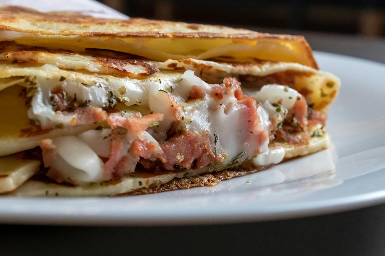 Ham and Gruyere crepes folded with melted cheese and ham on a white plate