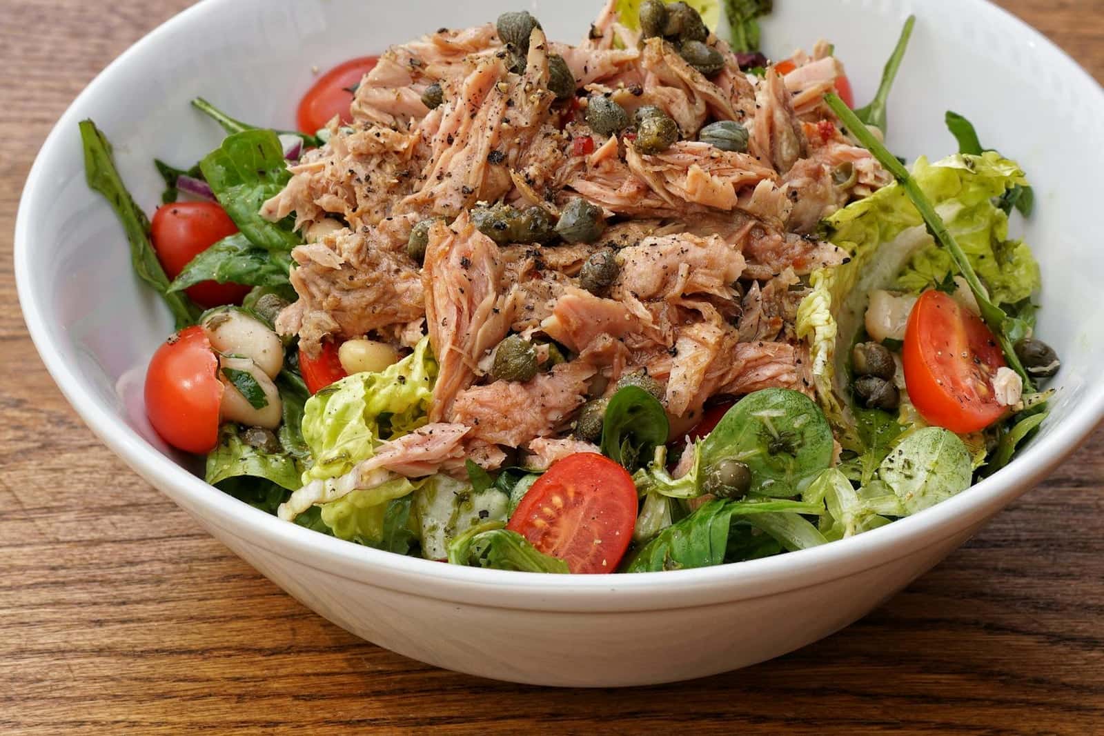 Mediterranean tuna and white bean salad with tomatoes, greens, capers, and herbs in a bowl