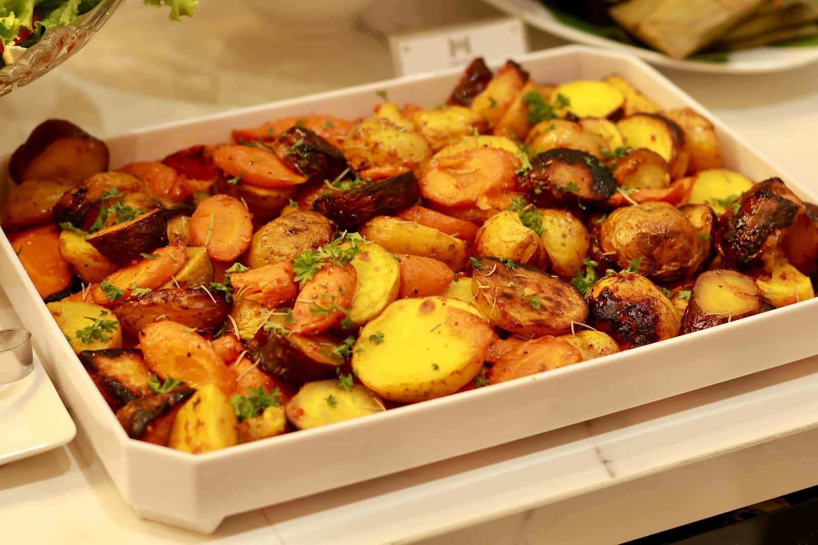 Honey glazed roasted root vegetables with carrots and potatoes in a white baking dish