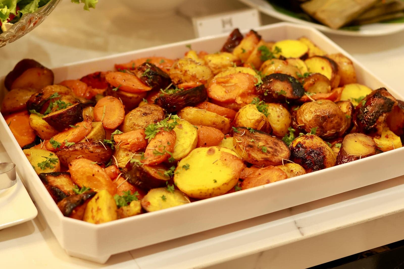 Honey glazed roasted root vegetables with carrots and potatoes in a white baking dish