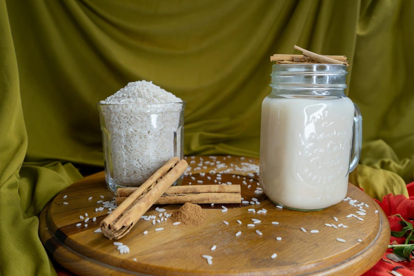 Horchata in a glass jar with rice and cinnamon sticks on a wooden surface