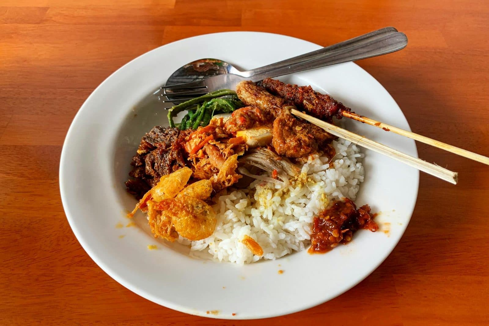 Indonesian nasi campur with rice, meat, vegetables, and sambal on a plate
