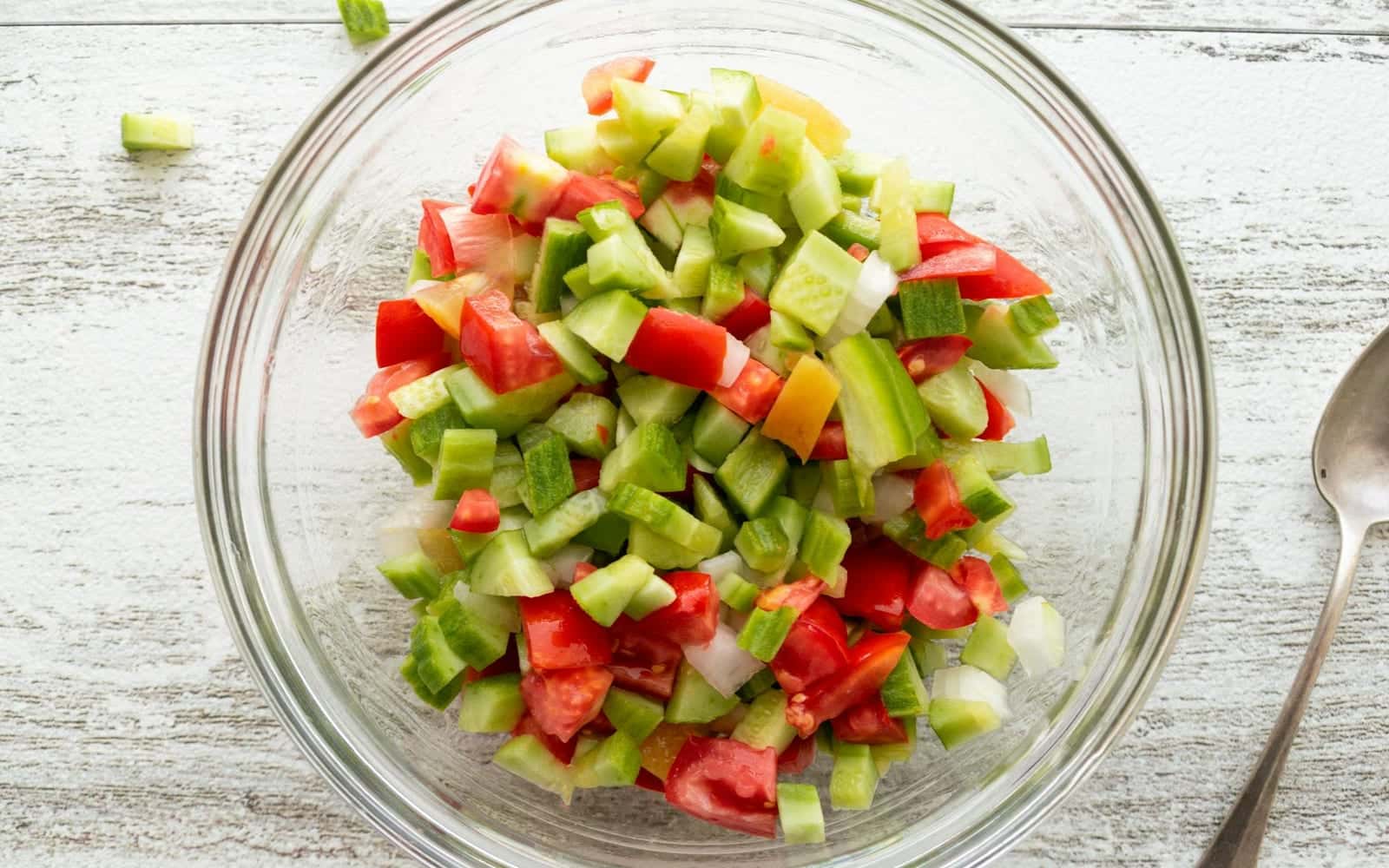 Israeli chopped salad with cucumber, tomato, and peppers in a glass bowl
