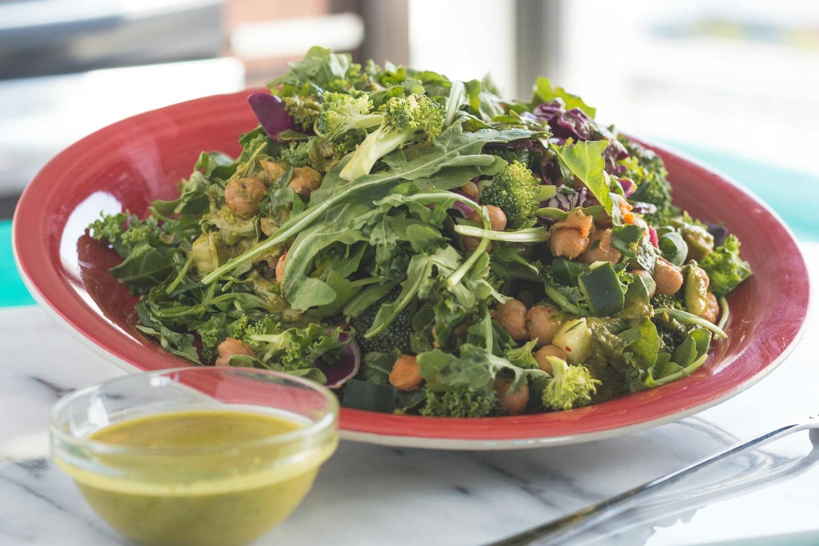 Kale Caesar salad with crispy chickpeas and green dressing on a red plate