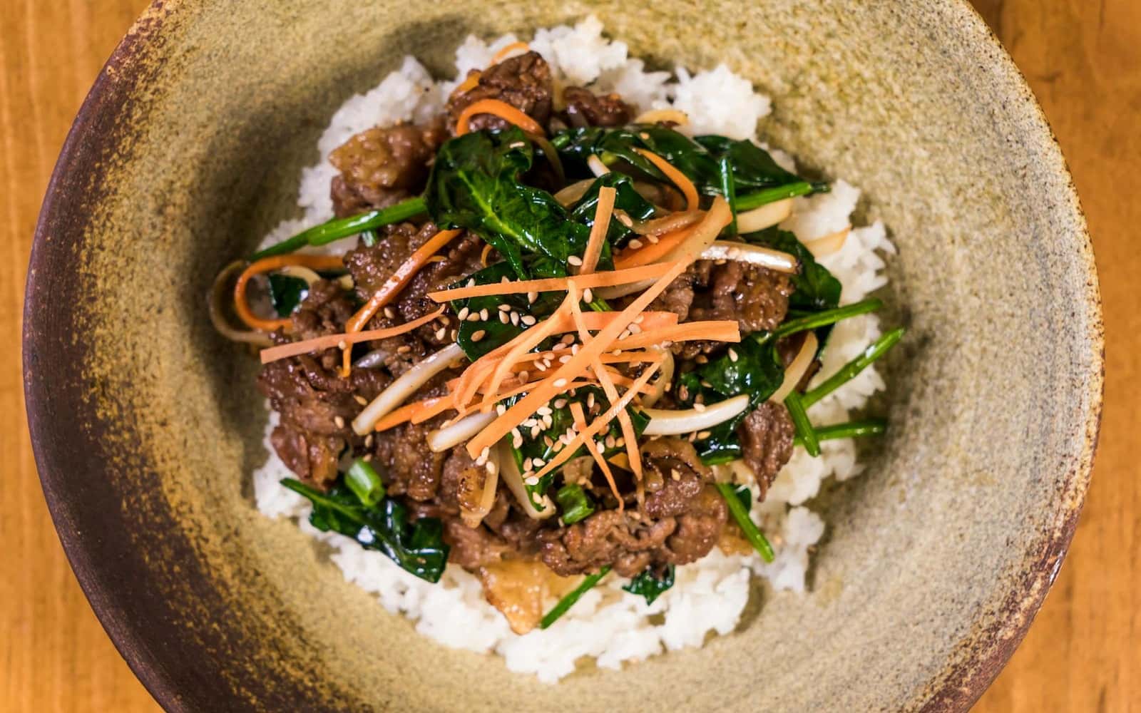 Korean beef bulgogi bowl with rice, vegetables, scallions, and glossy marinated beef